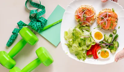 Plato saludable junto a mancuernas y cinta métrica
